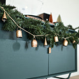 Decorative Christmas garland with gold bells on a green cabinet.