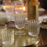 A set of two clear glass stemware items with a striped pattern on a brass tray