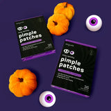 Two boxes of 'stay spooky pimple patches' with small pumpkins and eyeballs on a purple background.