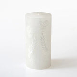 White candle with embossed design on a white background