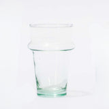 A clear recycled glass cup with a solid green tint and slight imperfections.
