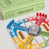 Trouble board game with dice and colorful pegs on a white background