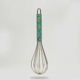 Metal whisk with a floral-patterned handle on a light gray background