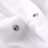 Close-up of a white romper with snap details on a white background