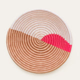 Round woven basket with color-block design on a white background