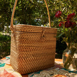 Woven picnic basket on a table with flowers in the background
