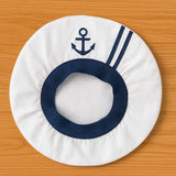 Round white hat with navy blue opening and anchor design on a wooden surface