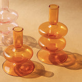 Conical-shaped orange glass candle holders with ridges, placed on a tan surface.