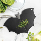 Bat-shaped cutting board with chopped vegetables on a marble surface