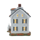 Model of a two-story house with lit windows on a white background