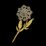 Gold brooch with a diamond-studded flower on a black background