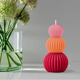 Stacked colorful candle with a vase of flowers on a gray background