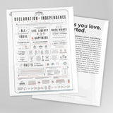 A decorative poster print titled 'Declaration & Independence' with a second overlapping poster showing additional text, photographed on a light gray background.