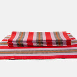 A handwoven placemat with red, pink, and brown stripes, placed on a white background.