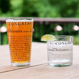 Two glasses with 'Congress' text on a wooden surface with a blurred green background