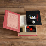 The image shows the Scattergories Vintage Bookshelf Edition board game set out on a table, including the bookshelf box, category cards, scorepads, pencils, timer, and die.