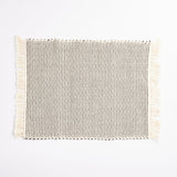 Handwoven placemat in natural and black cotton laid out flat on a white surface.