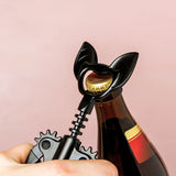 Black bottle opener with gear design being used on a bottle against a pink background