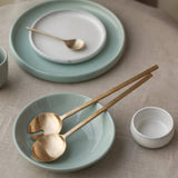 Two gold spoons in a light blue bowl.
