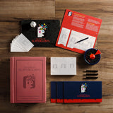 The image shows the Scattergories Vintage Bookshelf Edition board game set out on a table, including the bookshelf box, category cards, scorepads, pencils, timer, and die.