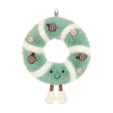 Green and white plush wreath toy covered in pinecone with a smiling face and feet.
