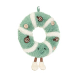 Green and white plush wreath toy covered in pinecone with a smiling face and feet.
