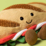 Plush toy shaped like a sandwich with a smiling face on a green background