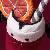 A plush toy shaped like a vampire drink in a glass, with a deep red body, white rim, black wings, black feet, a striped straw, and an orange slice decoration on a white background.