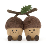 Two plush acorn toys with faces and a twig on a white background