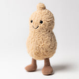 A soft plush toy resembling a peanut with a beige body, brown boots, and a smiling face.