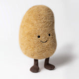 A plush toy resembling a potato with a golden-brown fur-like texture, with a smiling face, bean-shaped body, and corduroy boots.