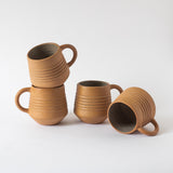 A set of four beige ceramic mugs with a handle, placed on white background.