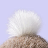Close-up of a fluffy white bunny tail against a light purple background