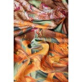 Draped fabric featuring a vibrant botanical print with large orange and yellow flowers, green leaves, and brown patterns on a beige background.