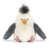 A plush toy seagull with soft cream fur, dark grey wings, thin pink legs, and a dark grey tuft on its head.