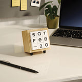 Small wooden calendar on a desk with a laptop and pen in the background