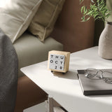 Wooden block calendar on a table with a bed and plant in the background