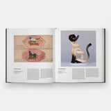 Open book showing illustrations of cats and a sculpture on a white background