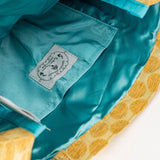 Close-up of a label on a piece of fabric with teal and yellow patterns.