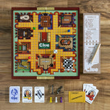 Clue board game set on a wooden surface with cards and pieces.