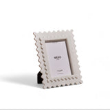 A white marble frame with a rectangular photo placed in the center, standing upright on a plain background.