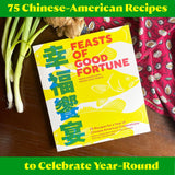 Book titled 'Feasts of Good Fortune' with Chinese-American recipes on a wooden surface.