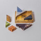 Seven colorful gemstone pieces in various shapes placed on a wooden board, with the gemstone types appearing subtly different in color.