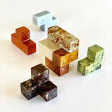 A multicolored gemstone Soma Cube Puzzle with a shadow on a white background.