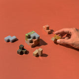 A multicolored gemstone Soma Cube Puzzle with a shadow on a red background.