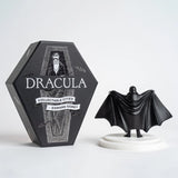Black figurine of a vampire next to its packaging with 'Dracula' text on a white background