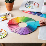 Color swatch playing cards on a table with color samples and a hand holding a color card.