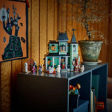 Toy house set on a shelf with decorative items against a warm-toned wall.