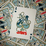 Playing card with 'Jaws' design on a background of more playing cards.