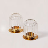 A set of two clear borosilicate glass lantern candle holders with brass finish metal bases.